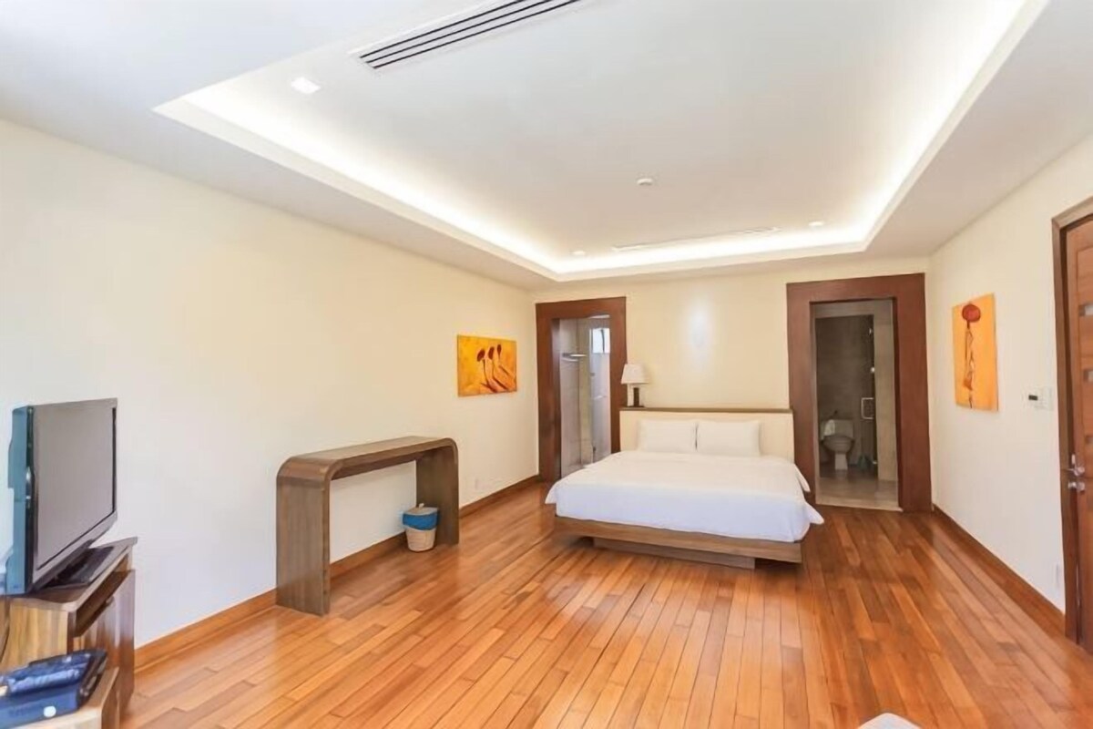 Een moderne hotelkamer met een houten vloer, een bed, een televisie en een bureau.