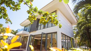 Une maison moderne à deux étages, dotée de grandes fenêtres et d’un patio couvert.