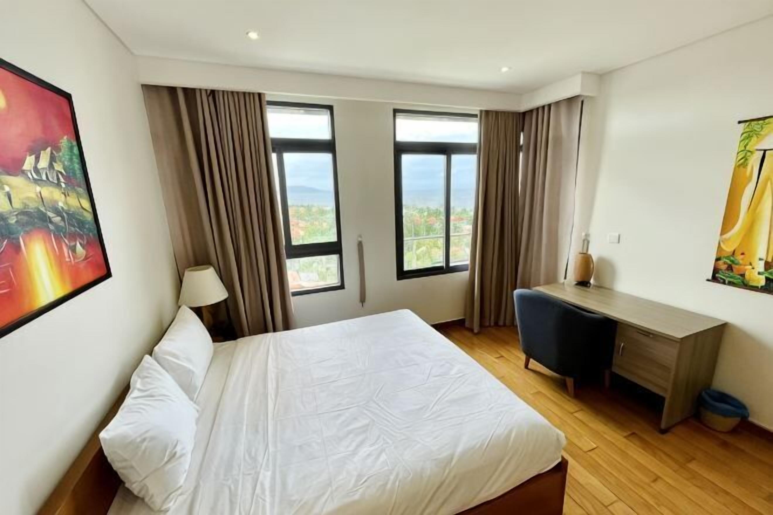 Ett hotellrum med en säng, ett skrivbord och stora fönster med utsikt.