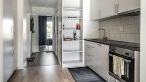 A modern kitchen with white cabinets, a black countertop, and a built-in oven. - 2 Bedroom Cozy City Apartment in Bromma (Bromma)