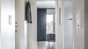 A hallway with a hexagonal patterned floor, a coat rack, and a view into a room with a table and a window. - 2 Bedroom Cozy City Apartment in Bromma (Bromma)