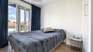 A bedroom with a bed, a bedside table with a lamp, a window with curtains, and a view of the outside. - 2 Bedroom Cozy City Apartment in Bromma (Bromma)