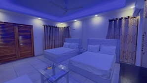 A bedroom with two beds, a glass table, and a ceiling fan. - Hotel Blue Sky (Dhaka)
