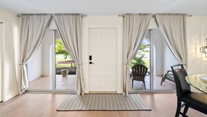 A room with a sliding glass door leading to an outdoor area, a small rug, and a table with chairs.