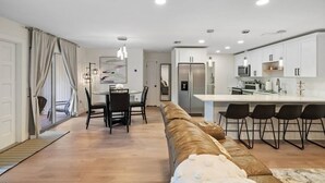 A modern kitchen with white cabinets, stainless steel appliances, and black bar stools.