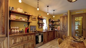 Une cuisine avec des meubles de rangement en bois, un four encastré et une table à manger avec des chaises.