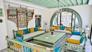 A traditional room with a sofa set, a dining table, and a decorative mirror. - Dar Gino - Maison d'hôtes (Kelibia)
