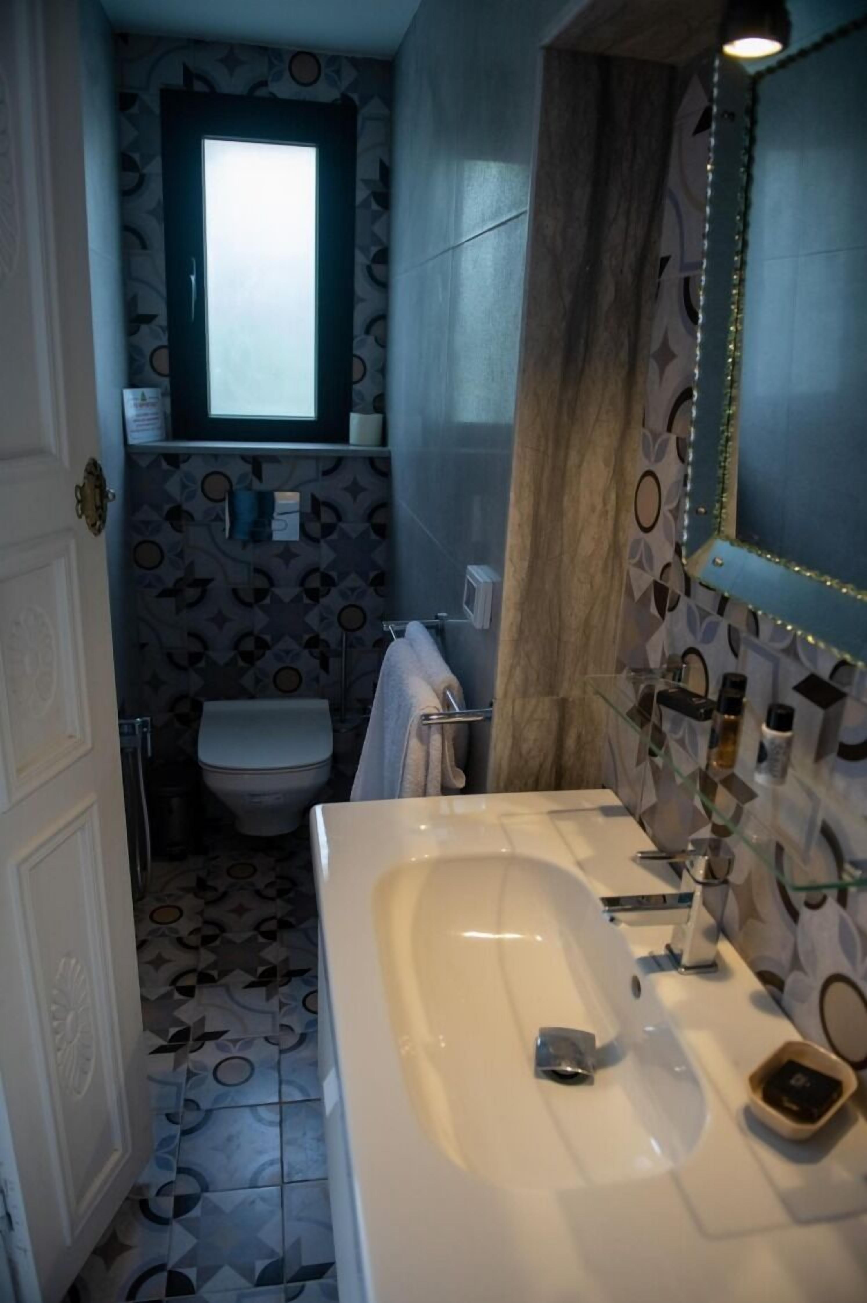 Ein Badezimmer mit einem weißen Waschbecken, einem Spiegel und einer Toilette.