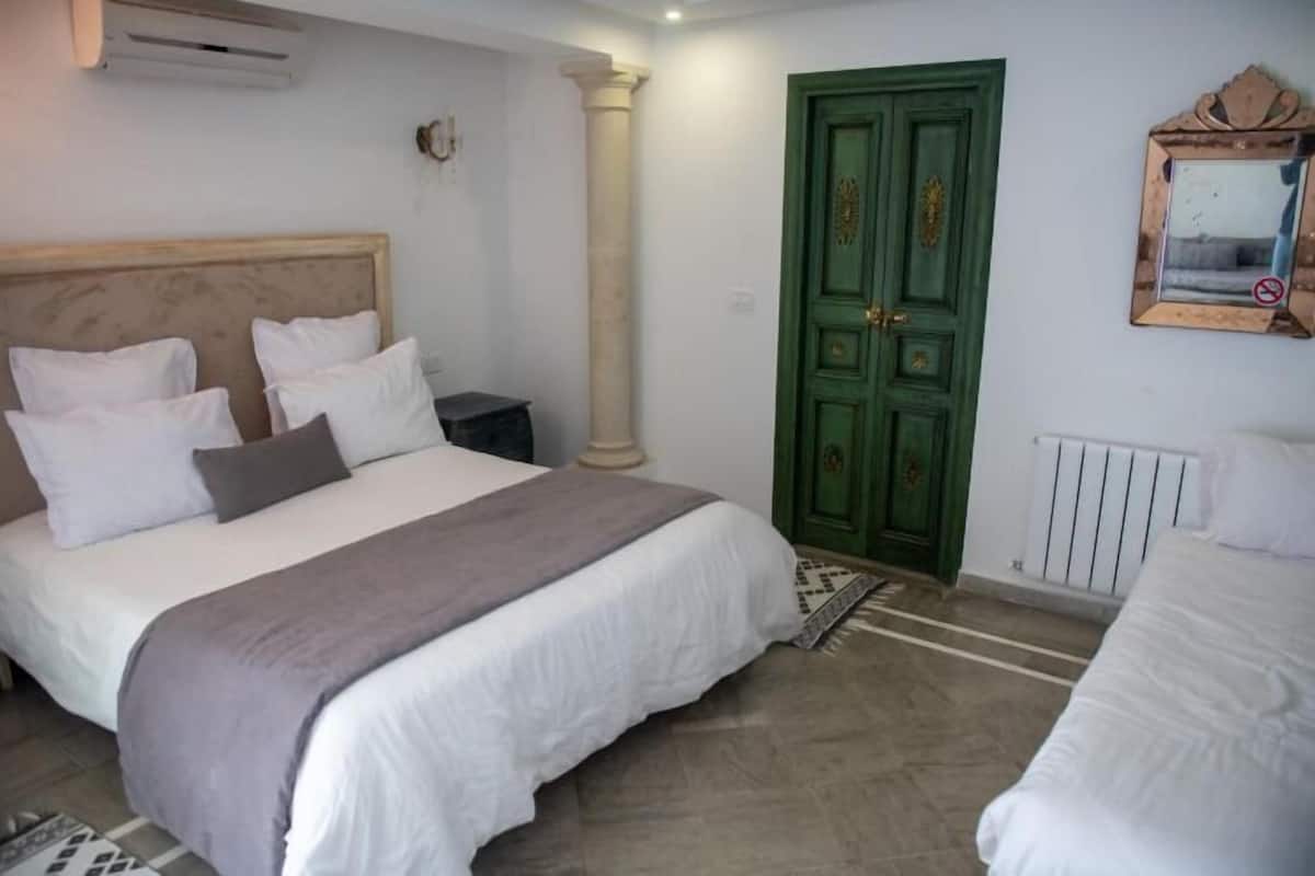 A bedroom with a large bed, a green door, and a radiator.