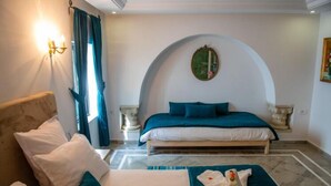 A bedroom with a bed, a sofa, a wall-mounted light, and a mirror. - Dar Gino - Maison d'hôtes (Kelibia)