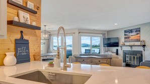 Eine moderne Küche mit einer großen Kochinsel, Holzregalen und Blick ins Freie.