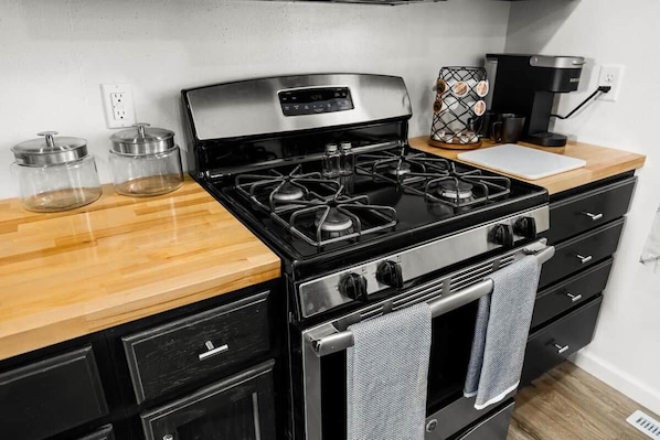 A kitchen with a stove, oven, and coffee maker. There are two glass jars on the counter.