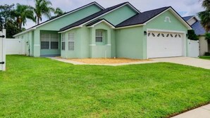 A single-story house with a garage, a well-maintained lawn, and a cloudy sky. - Pool home 5 miles to Disney! Great for families! (Kissimmee)