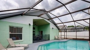 A covered swimming pool with lounge chairs and a patio area. - Pool home 5 miles to Disney! Great for families! (Kissimmee)