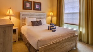 A neatly made bed with a wooden headboard, two bedside lamps, and a window with curtains. - Tuscana Resort Retreat (Kissimmee)