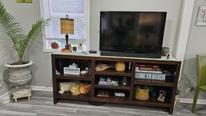 Una sala de estar con un mueble de madera para entretenimiento, un televisor y una planta en maceta.