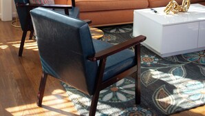 Un salon avec un canapé, des fauteuils, une table basse et un tableau accroché au mur.