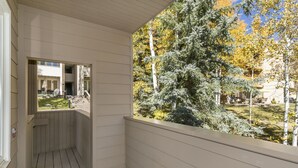 Un espace extérieur abrité offrant une vue sur un jardin et des arbres.