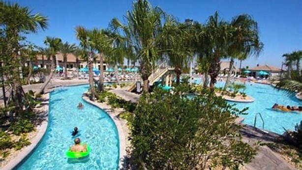 A large outdoor swimming pool with multiple lanes, surrounded by palm trees and lounge areas. - Championsgate-Free Water park/18 mins DisneyWorld (Davenport)
