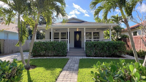 A single-story house with a front porch, a small front yard with a pathway, and a wooden fence in the background. - LIT's Palma Home - Near Beach, Downtown, Shopping, & More!! (West Palm Beach)