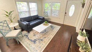 A living room with a dark-colored sofa, a white coffee table, a patterned rug, a light blue chair, and a potted plant. - LIT's Palma Home - Near Beach, Downtown, Shopping, & More!! (West Palm Beach)
