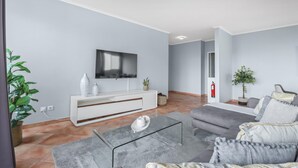Una sala de estar moderna con un televisor de pantalla plana, un sofá gris y una mesa de centro de vidrio.