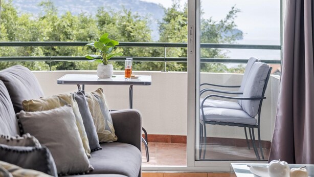 Un balcón con un sofá, una mesa con una planta y una silla.