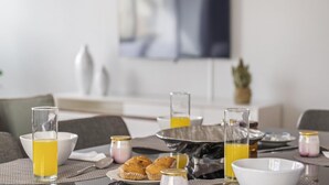 Preparación para el desayuno, una mesa para dos personas con platos, vasos y un bol.
