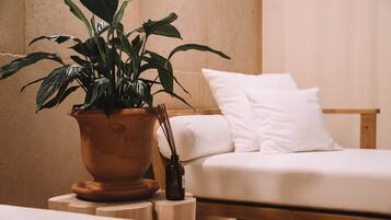 Relax in a serene bedroom with a lush plant, a wooden bed, and a cozy atmosphere.