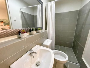Bathroom features a pedestal sink, toilet, and shower area with a curtain.