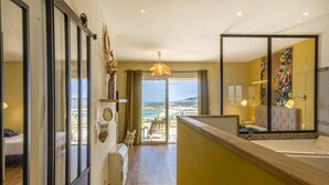 Ett hotellrum med balkong, en säng, ett skrivbord och utsikt över havet.