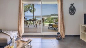 A room with a sliding glass door leading to a balcony with a view of the sea. - Casa Ghju (Algajola)