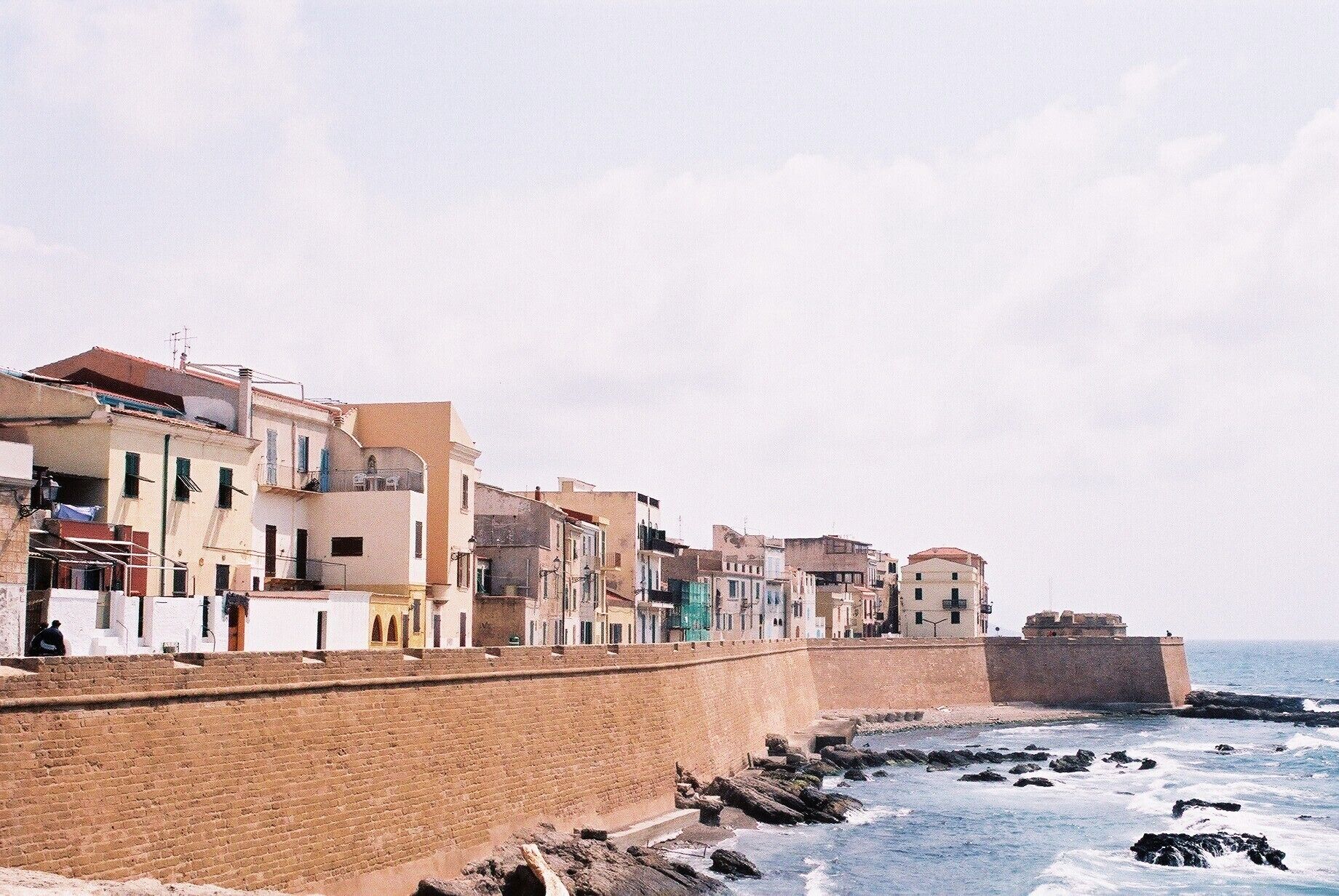 Un pueblo costero con edificios a lo largo de un muro de piedra frente al mar.
