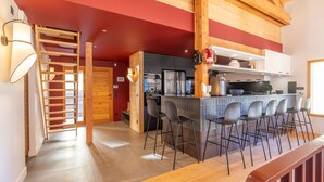 Une cuisine moderne avec un îlot central, des tabourets de bar et un escalier en bois.