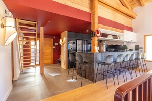 Una cocina moderna con una isla central, taburetes de bar y una escalera de madera.