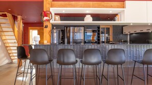 Une cuisine moderne avec un coin bar, des appareils en acier inoxydable et un escalier en bois.