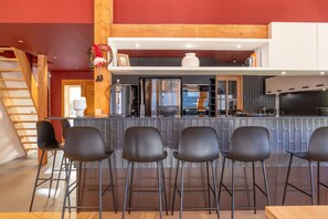 Una cocina moderna con barra, electrodomésticos de acero inoxidable y una escalera de madera.
