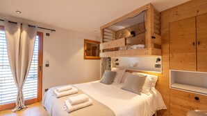 Une chambre avec un lit superposé, une armoire en bois, une fenêtre avec des rideaux et une table de chevet.
