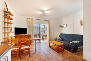 A living room with a sofa, coffee table, TV, wooden chairs, and a dining table. - Holiday Apartment "Playita" with Sea View, Private Terrace & Wi-Fi (Valle Gran Rey)