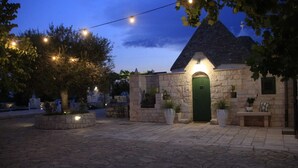 A stone building with a green door, surrounded by potted plants and string lights. - Villa 'Trulli Orma' with Private Pool, Wi-Fi and Air Conditioning (Locorotondo)