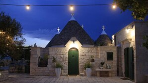 A stone building with a green door, potted plants, and a paved courtyard. - Villa 'Trulli Orma' with Private Pool, Wi-Fi and Air Conditioning (Locorotondo)