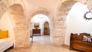 A room with stone walls, a wooden bench, a bed, and a dresser. - Villa 'Trulli Orma' with Private Pool, Wi-Fi and Air Conditioning (Locorotondo)