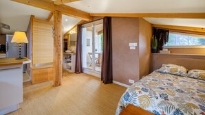A bedroom with a bed, a desk, a lamp, and a sliding glass door leading to a balcony. - Loft 50m² au calme avec vue splendide piscine (Les Adrets-de-l'Estérel)