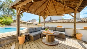A wooden deck with a covered seating area, a pool, and potted plants. - Loft 50m² au calme avec vue splendide piscine (Les Adrets-de-l'Estérel)