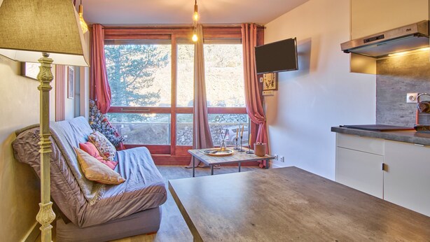 Ein gemütliches Wohnzimmer mit einer Couch, einem Tisch und einem an der Wand befestigten Fernseher.