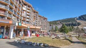 Ein mehrstöckiges Hotel mit Balkonen, einem Skiverleih und Blick auf eine Berglandschaft.
