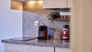 Eine Küche mit Betonfliesen, einer Kaffeemaschine, einem Glasbehälter und einer Nussknacker.