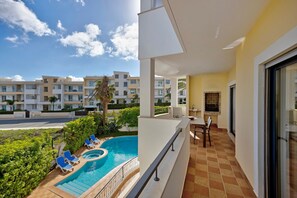A balcony with a pool, lounge chairs, a table, and a view of other buildings. - Chez Hélène et Paulo Apartment with Shared Pool, Wi-Fi, and Air Conditioning (Lagos)