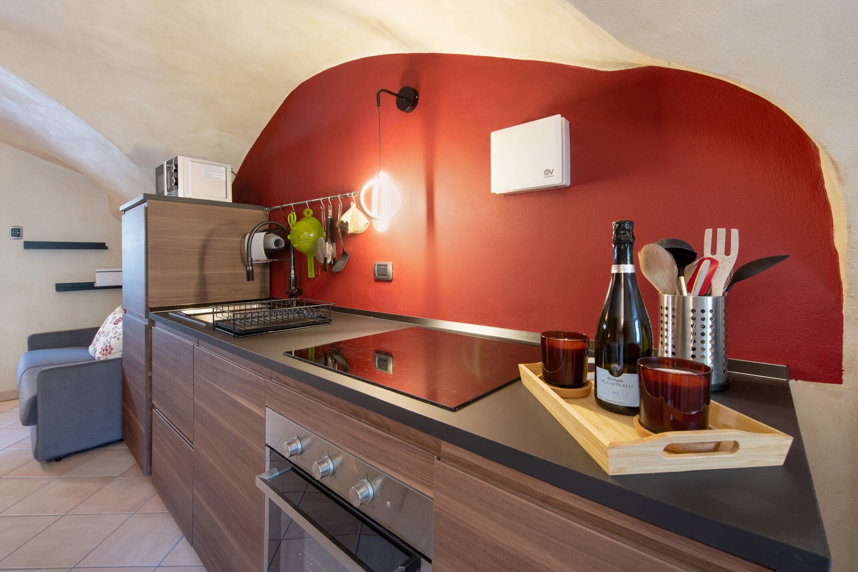 A modern kitchen with a red accent wall, a built-in oven, and a wooden countertop.