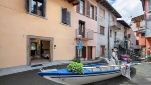 A narrow street with a row of colorful buildings, a small boat with a flag, and a statue of a person.